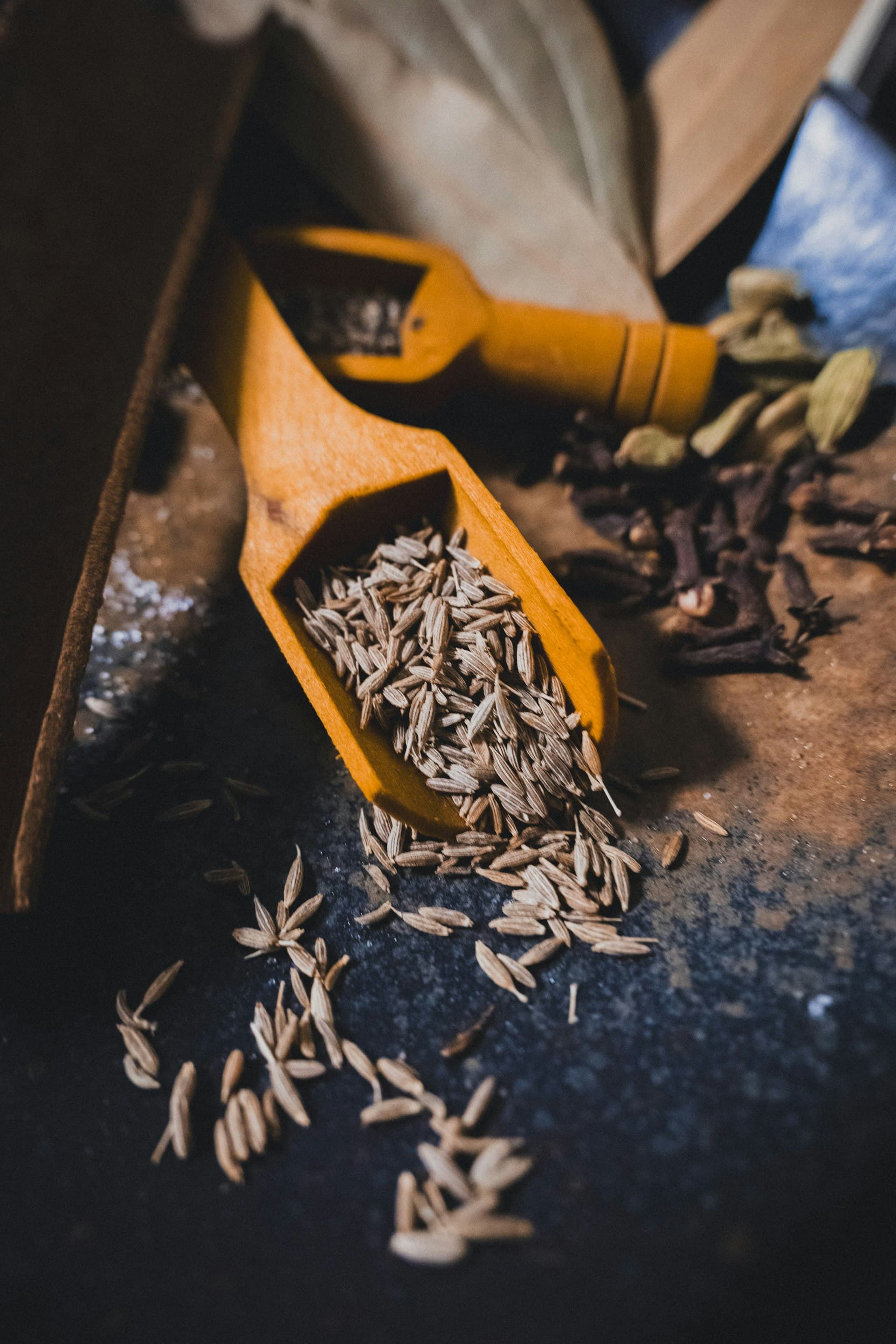 Whole cumin seeds in wooden scoops