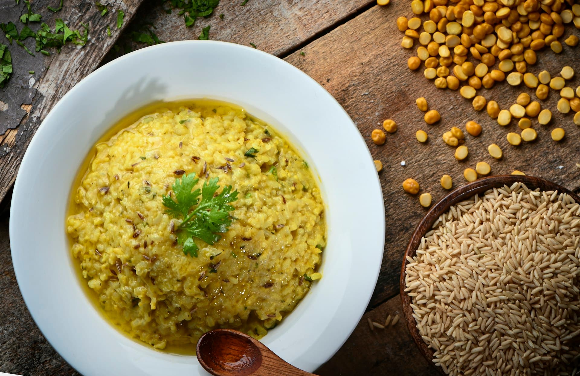 A bowl of yellow dal with lentils and spices on the side