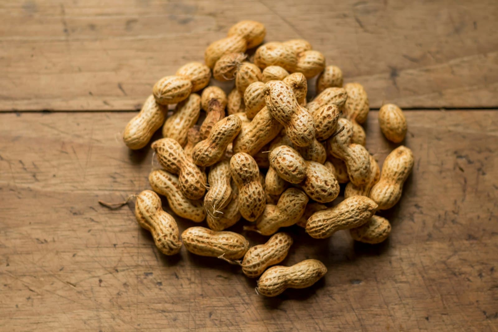 A heap of whole groundnuts (mungafali) on a wooden table
